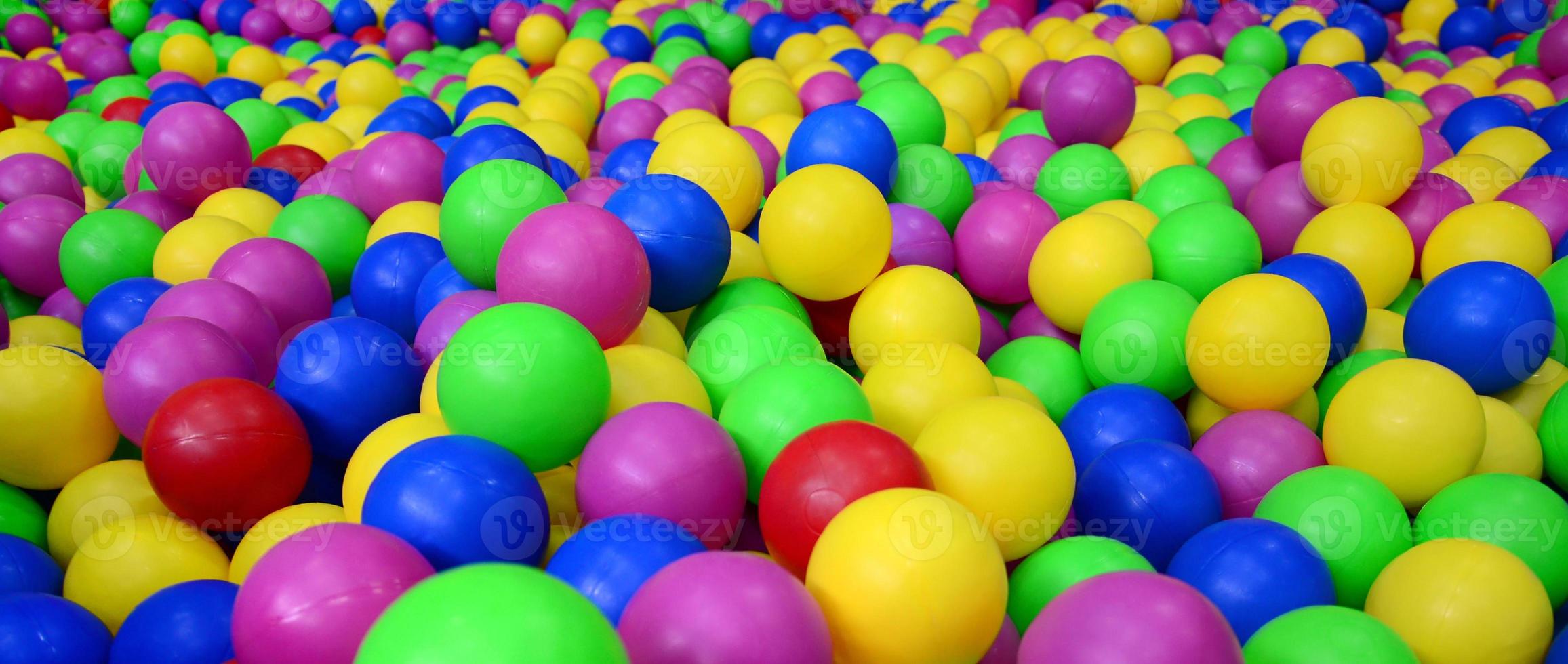 Many colorful plastic balls in a kids' ballpit at a playground. Close up pattern photo