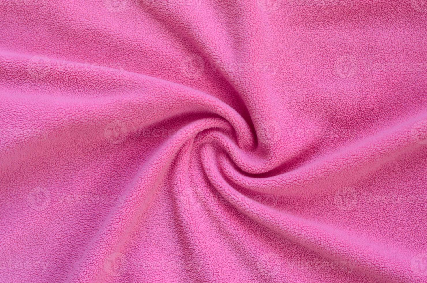 The blanket of furry pink fleece fabric. A background of light pink soft plush fleece material with a lot of relief folds photo
