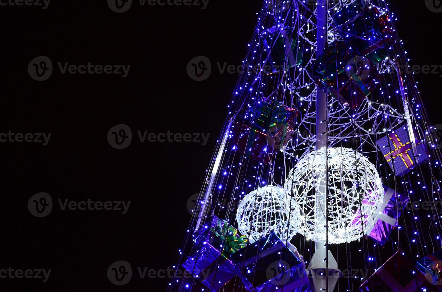 Fragment of the New Year tree. A lot of round lights of blue color are located on a conical frame photo