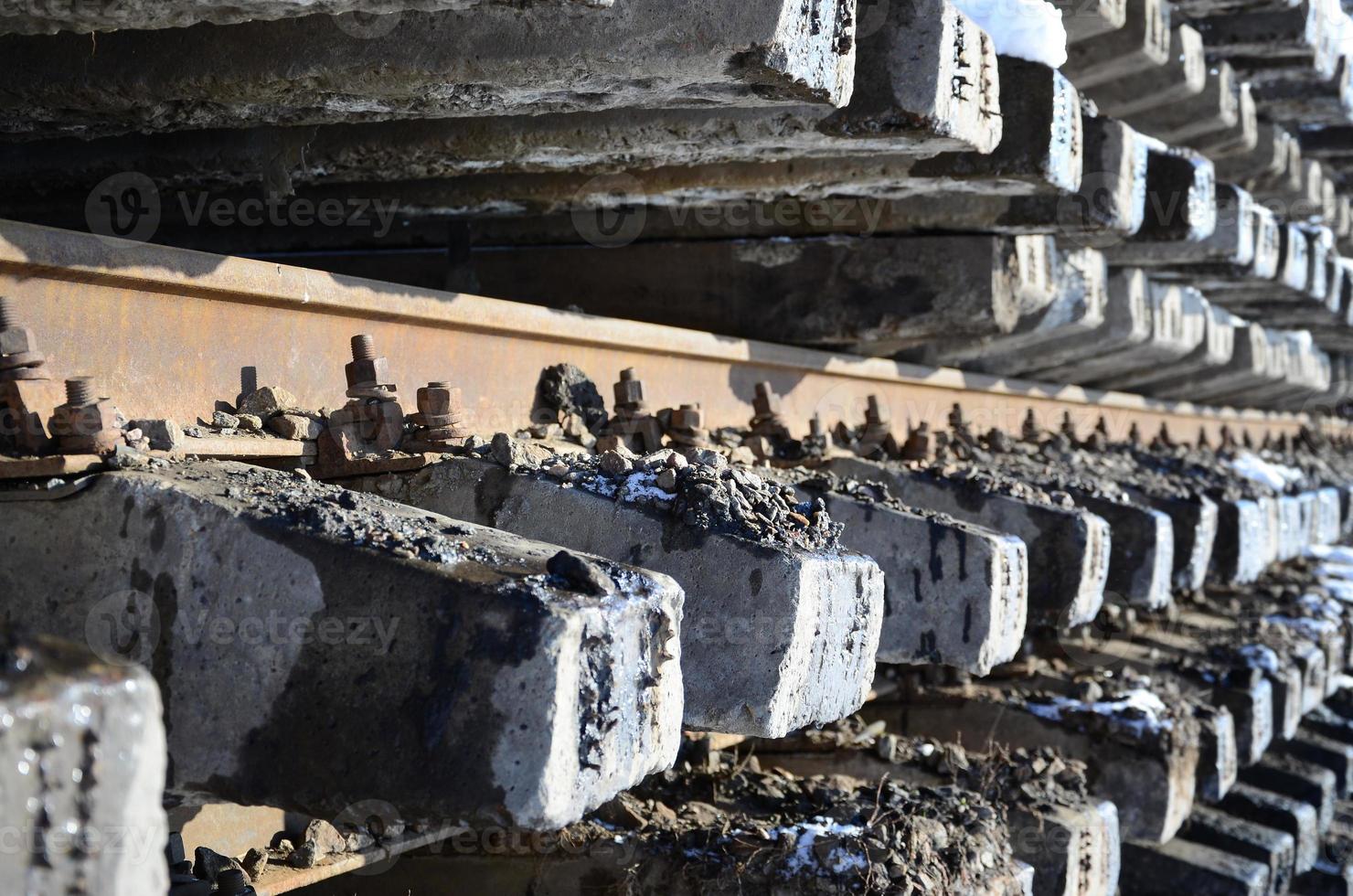 A lot of old rails and sleepers are stacked in a railway warehouse in winter. The concept of renewing a worn-out railway track photo