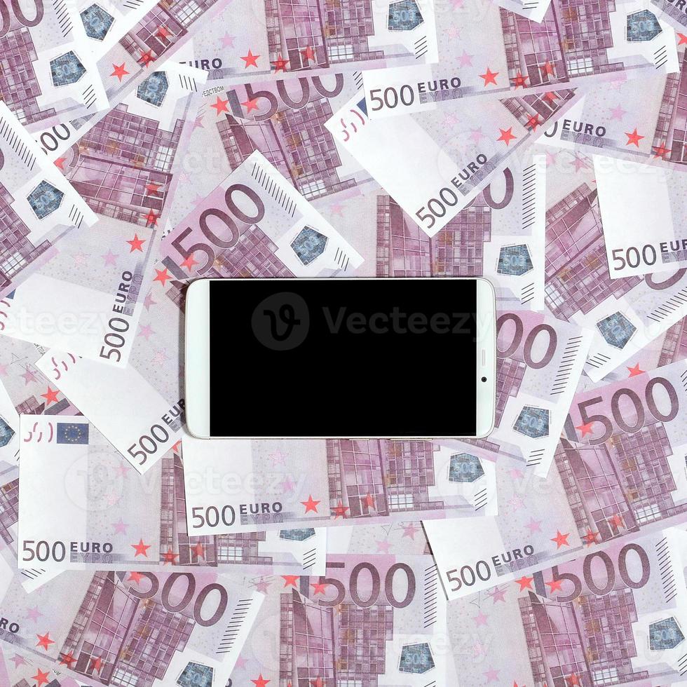 Purple 500 euro money bills and a smartphone with black screen. Copy space. The concept of online banking, money management and shopping with modern technology photo