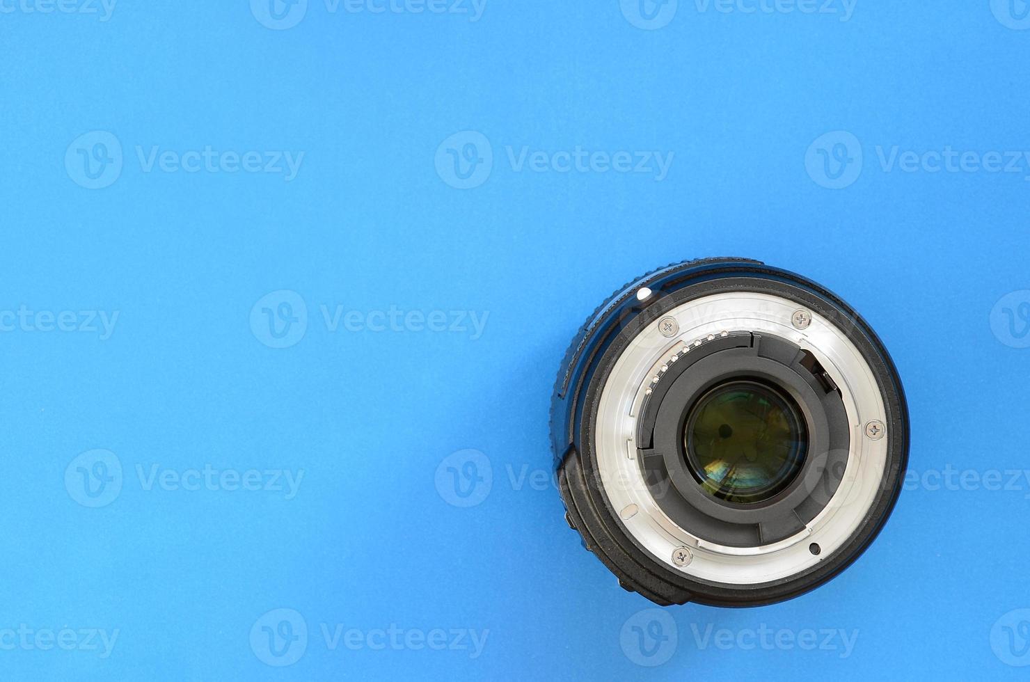 One photographic lense lie on a bright blue background. Space for text photo