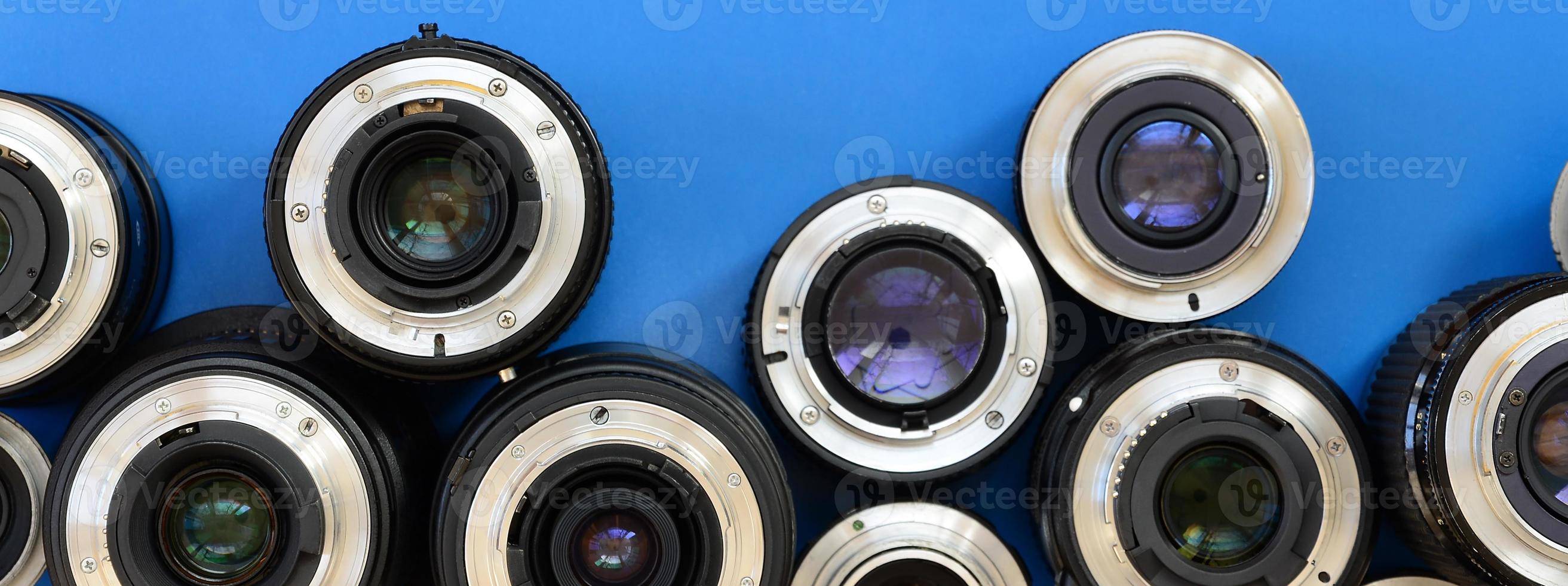 Several photographic lenses lie on a bright blue background. Space for text photo