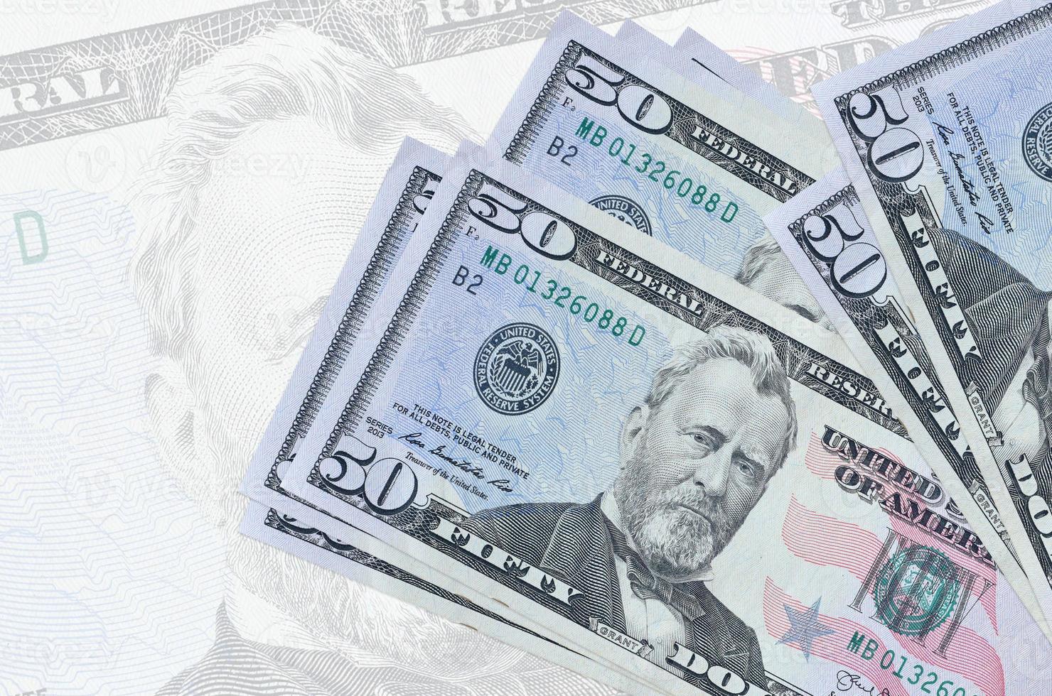 50 US dollars bills lies in stack on background of big semi-transparent banknote. Abstract presentation of national currency photo