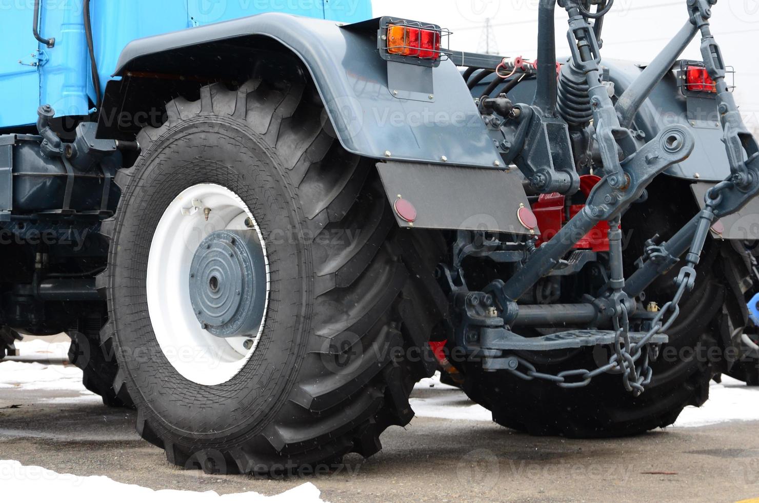 Wheels of back view of new tractor in snowy weather. Agricultural vehicle back view photo