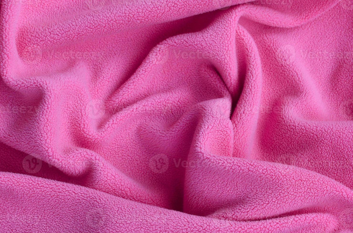 The blanket of furry pink fleece fabric. A background of light pink soft plush fleece material with a lot of relief folds photo