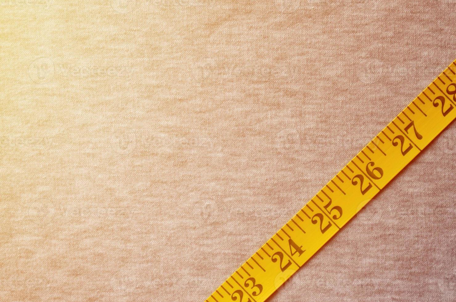 Yellow measuring tape lies on a gray knitted fabric photo