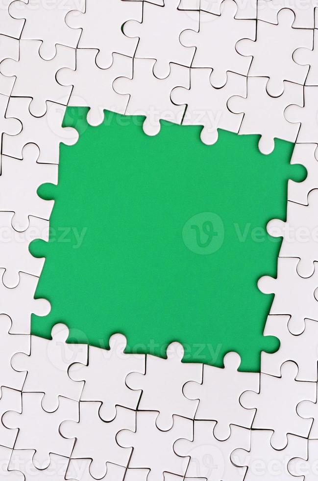 Framing in the form of a rectangle, made of a white jigsaw puzzle around the green space photo