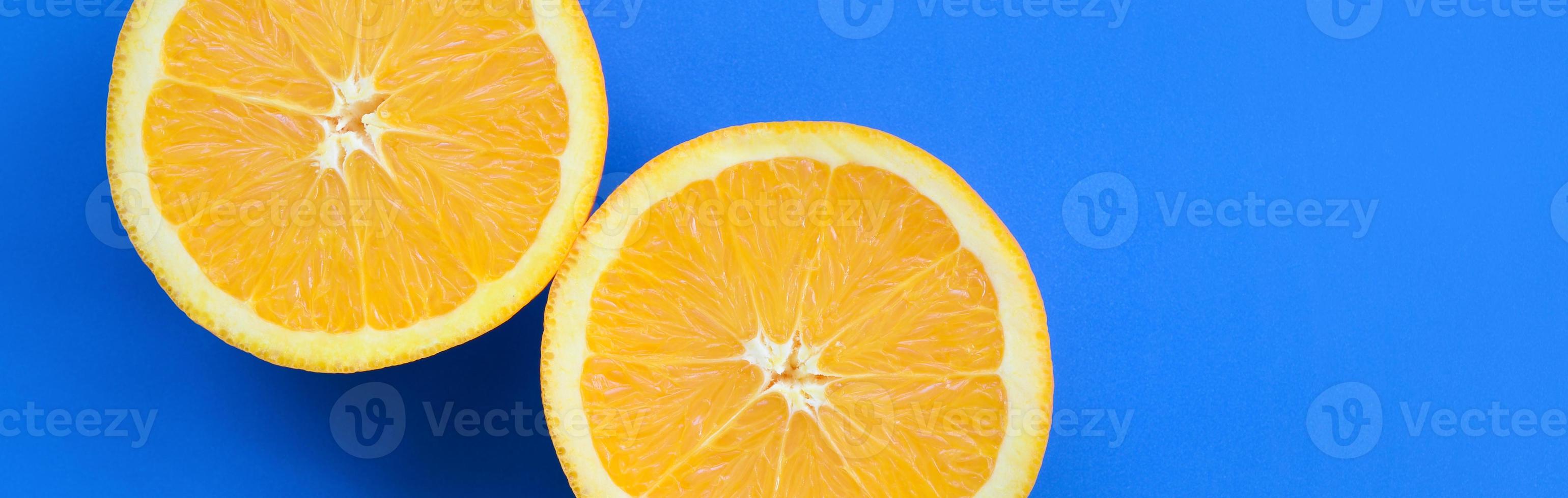 Top view of a several orange fruit slices on bright background in blue color. A saturated citrus texture image photo