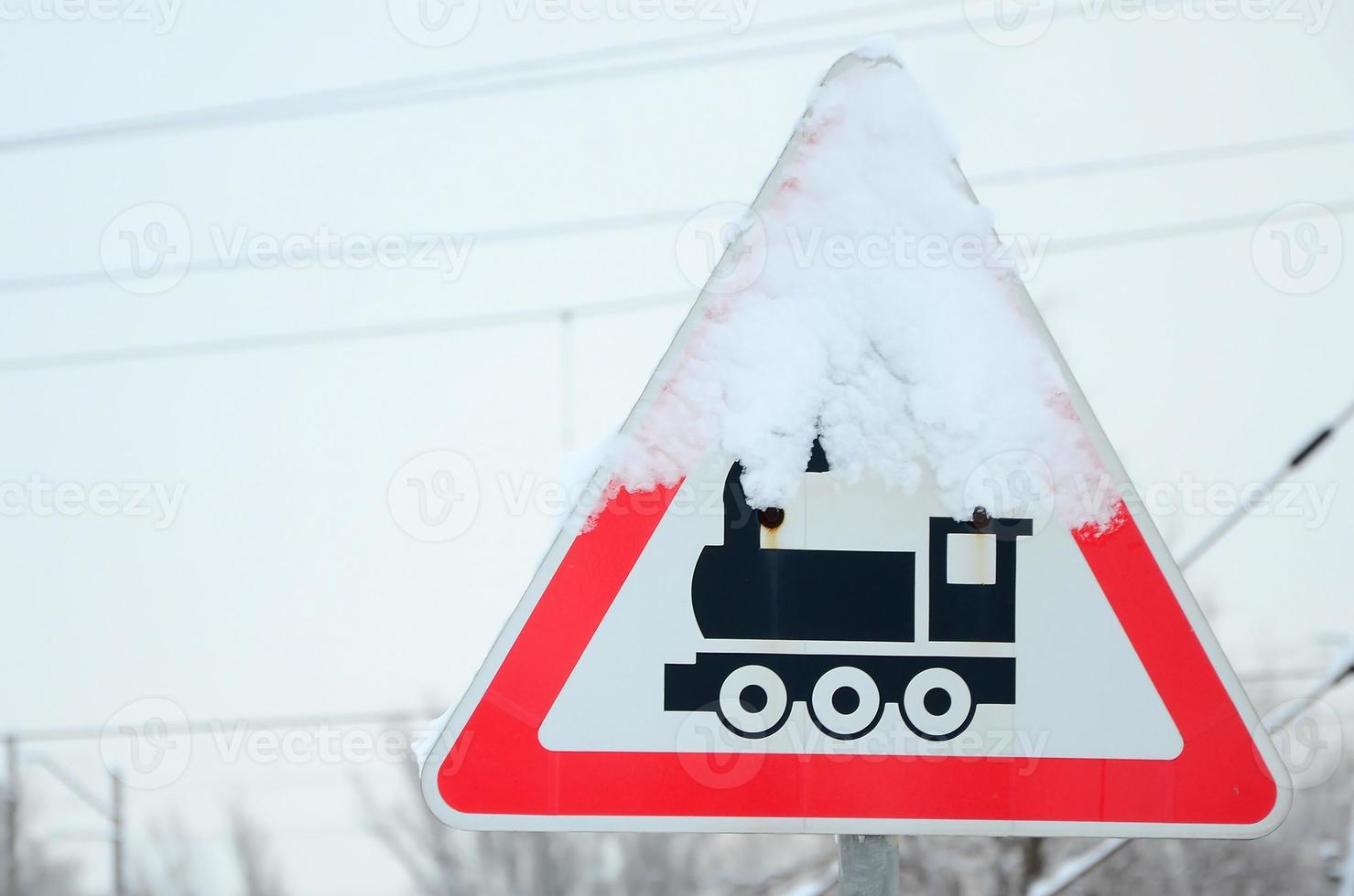 Railway crossing without barrier. A road sign depicting an old black locomotive, located in a red triangle photo