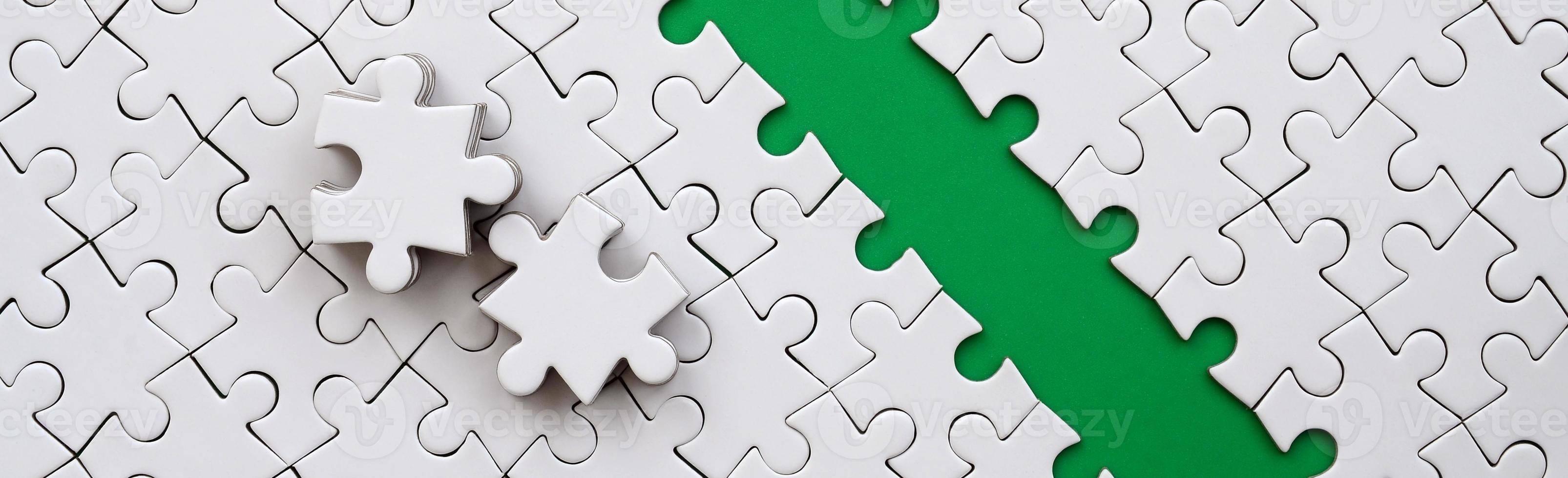 The green path is laid on the platform of a white folded jigsaw puzzle. The missing elements of the puzzle are stacked nearby. Texture image with space for text photo