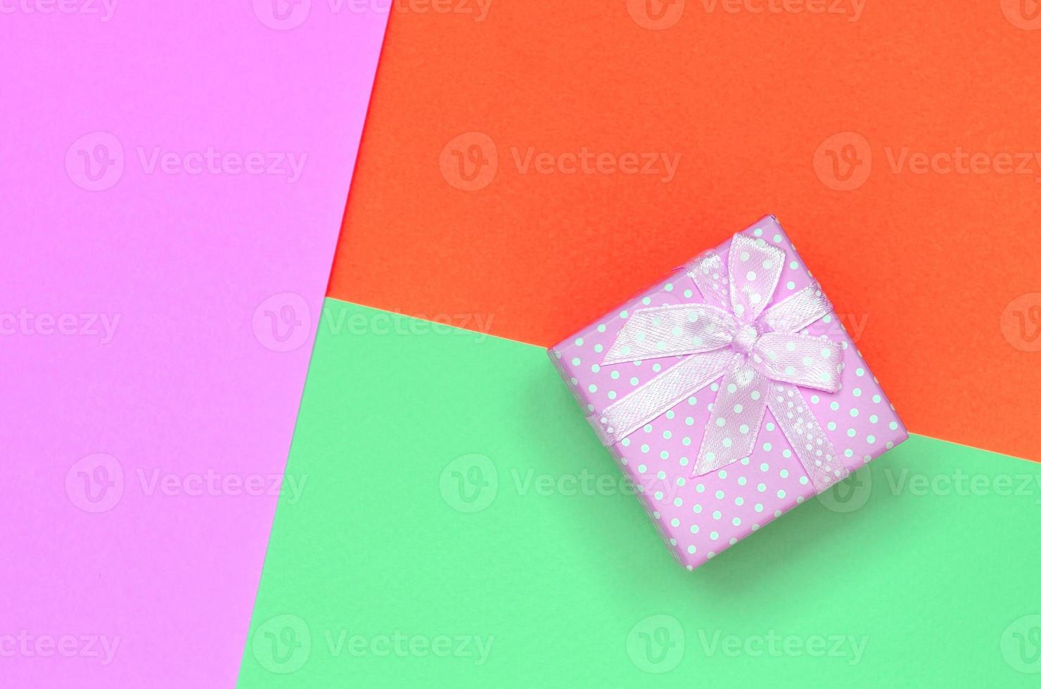 Small pink gift box lie on texture background of fashion pastel turquoise, red and pink colors paper photo