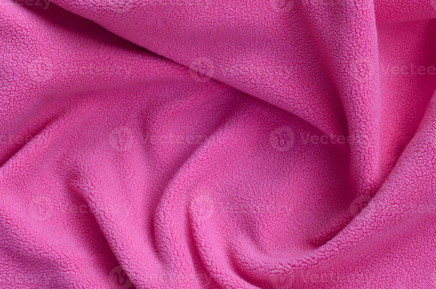 The blanket of furry pink fleece fabric. A background of light pink soft plush fleece material with a lot of relief folds photo