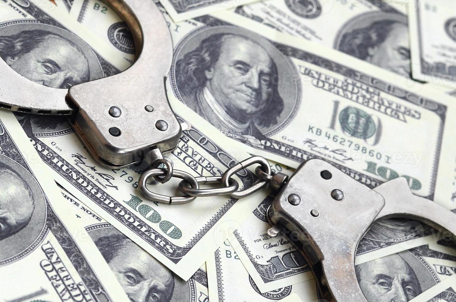 Police handcuffs lie on a lot of dollar bills. The concept of illegal possession of money, illegal transactions with US dollars. Economic Crime photo