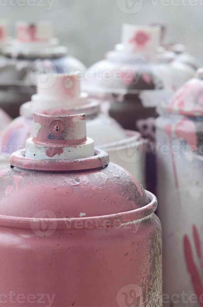 A lot of dirty and used aerosol cans of bright pink paint. Macro photograph with shallow depth of field. Selective focus on the spray nozzle photo