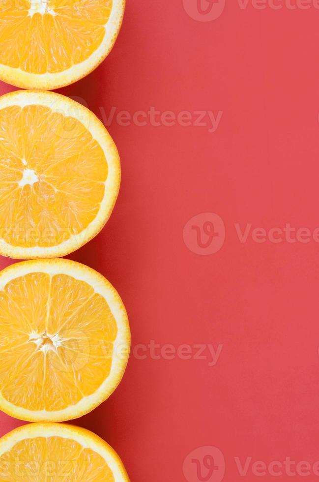 Top view of a several orange fruit slices on bright background in red color. A saturated citrus texture image photo