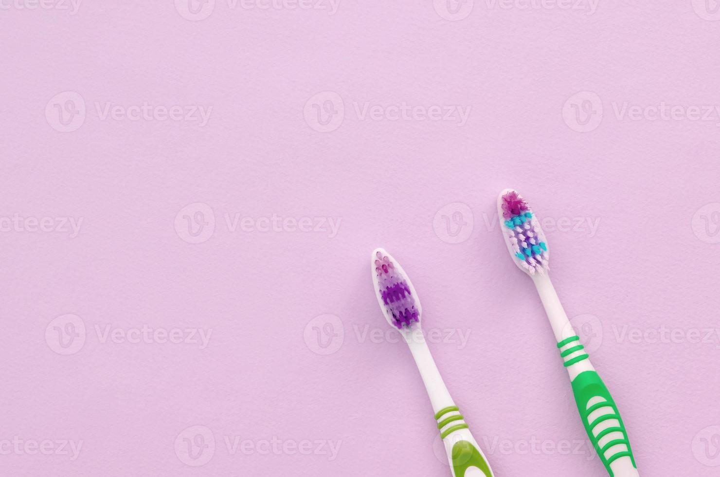 dos cepillos de dientes yacen sobre un fondo rosa pastel foto