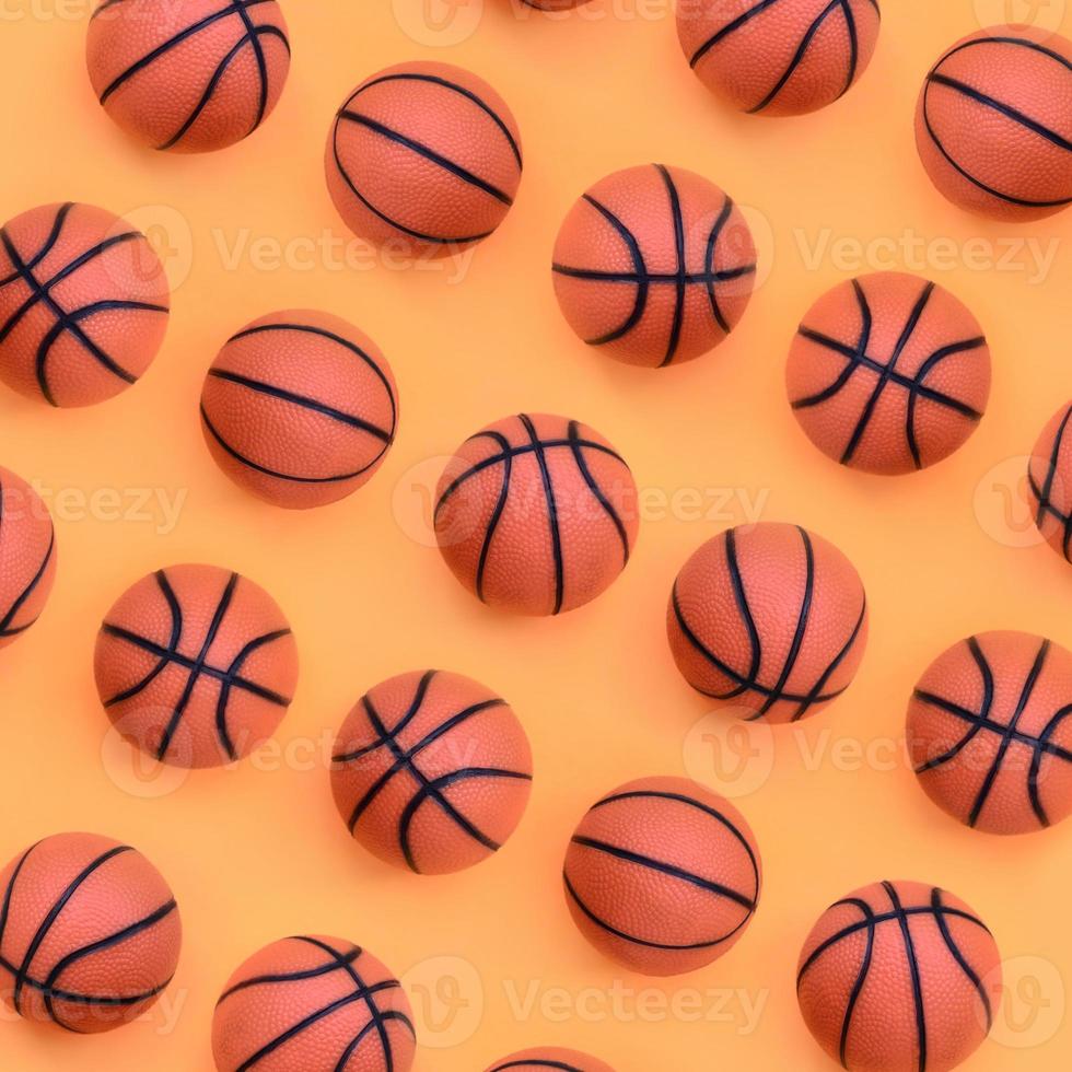 Many small orange balls for basketball sport game lies on texture background of fashion pastel orange color paper in minimal concept photo