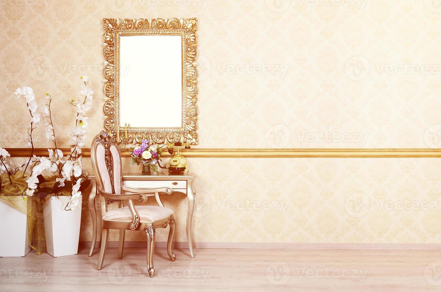 A fragment of a retro interior with a chair and table, on which is a telephone and a vase of flowers. Above the table hangs an empty picture frame for your photo