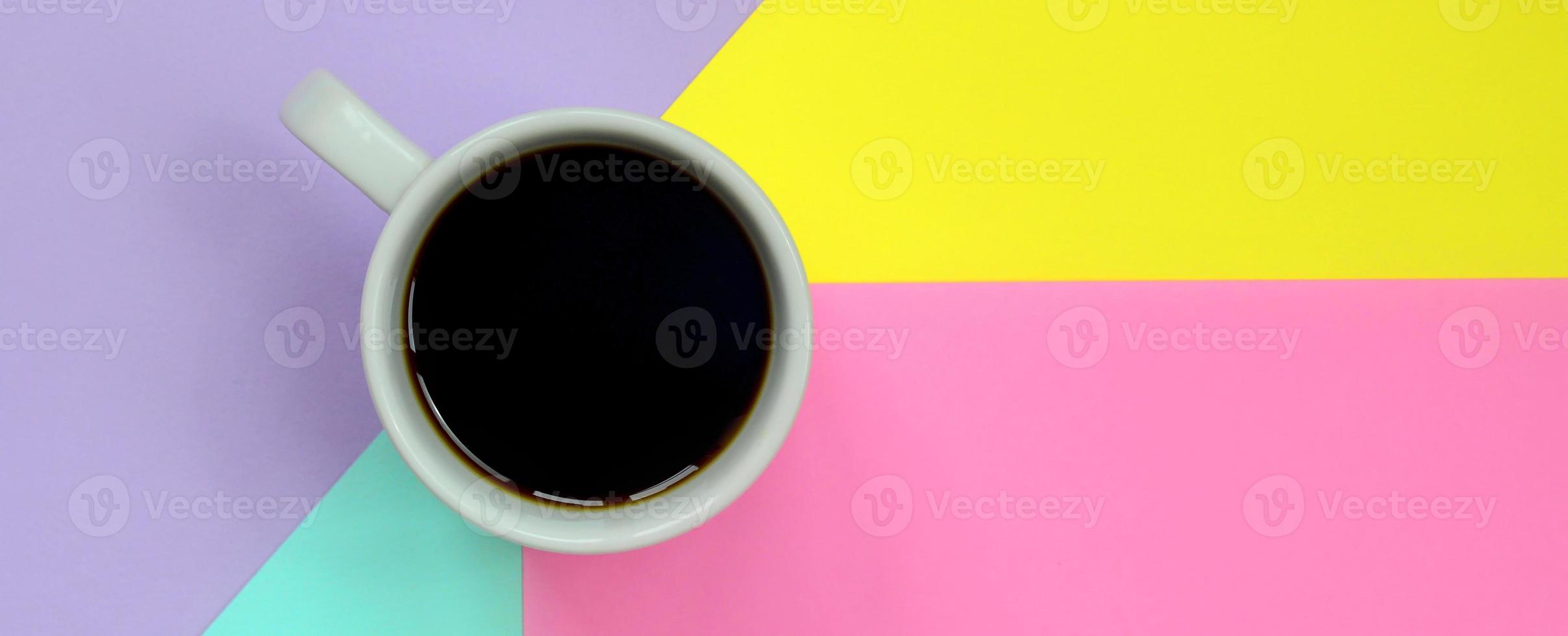 Small white coffee cup on texture background of fashion pastel blue, yellow, violet and pink colors paper in minimal concept photo