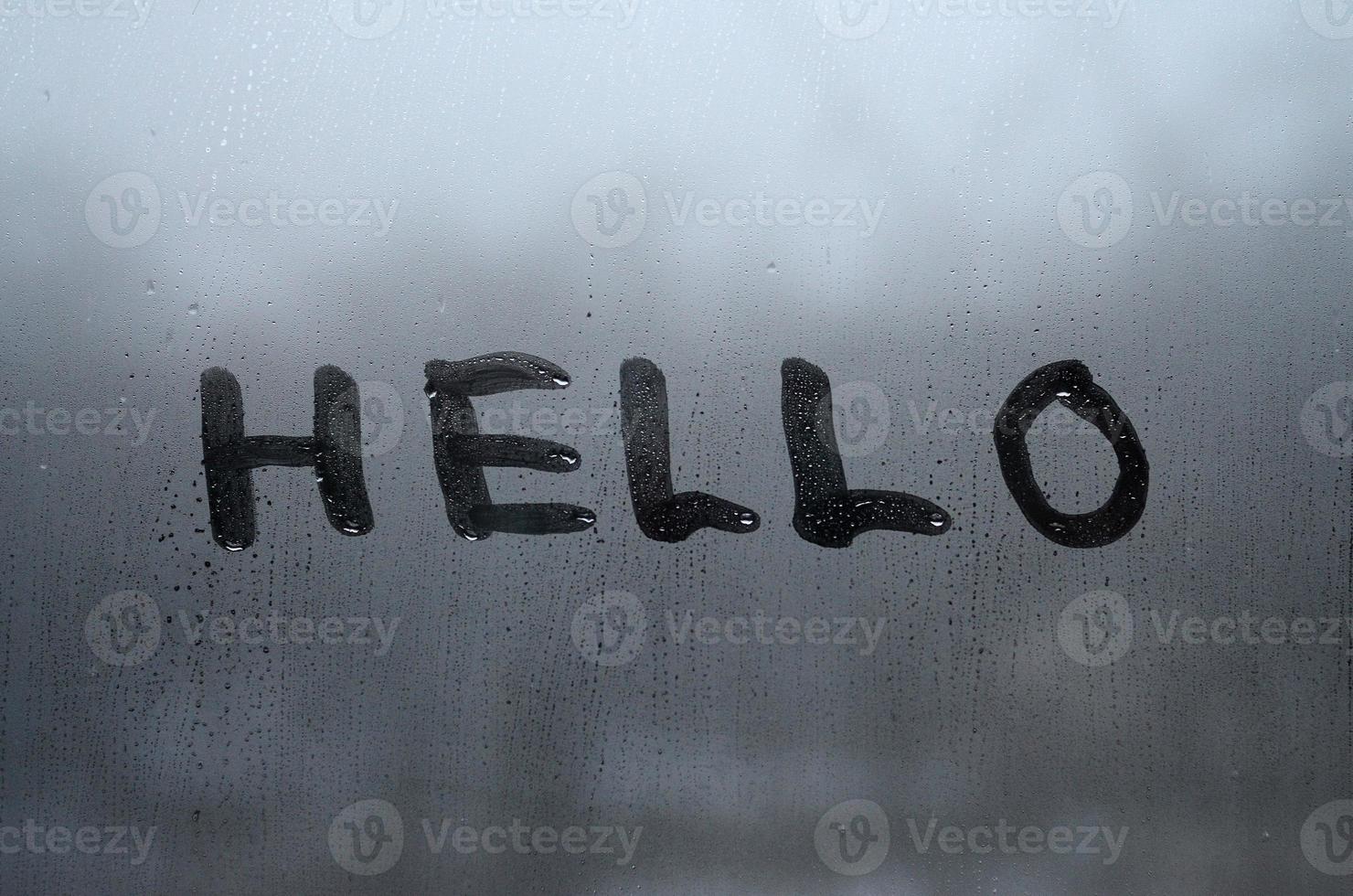 The English word Hello is written with a finger on the surface of the misted glass photo