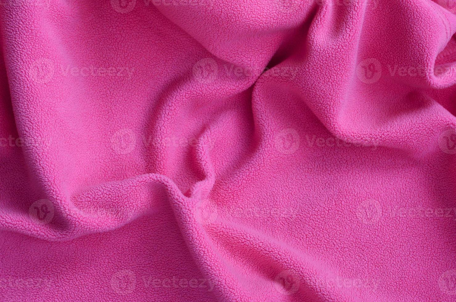 The blanket of furry pink fleece fabric. A background of light pink soft plush fleece material with a lot of relief folds photo
