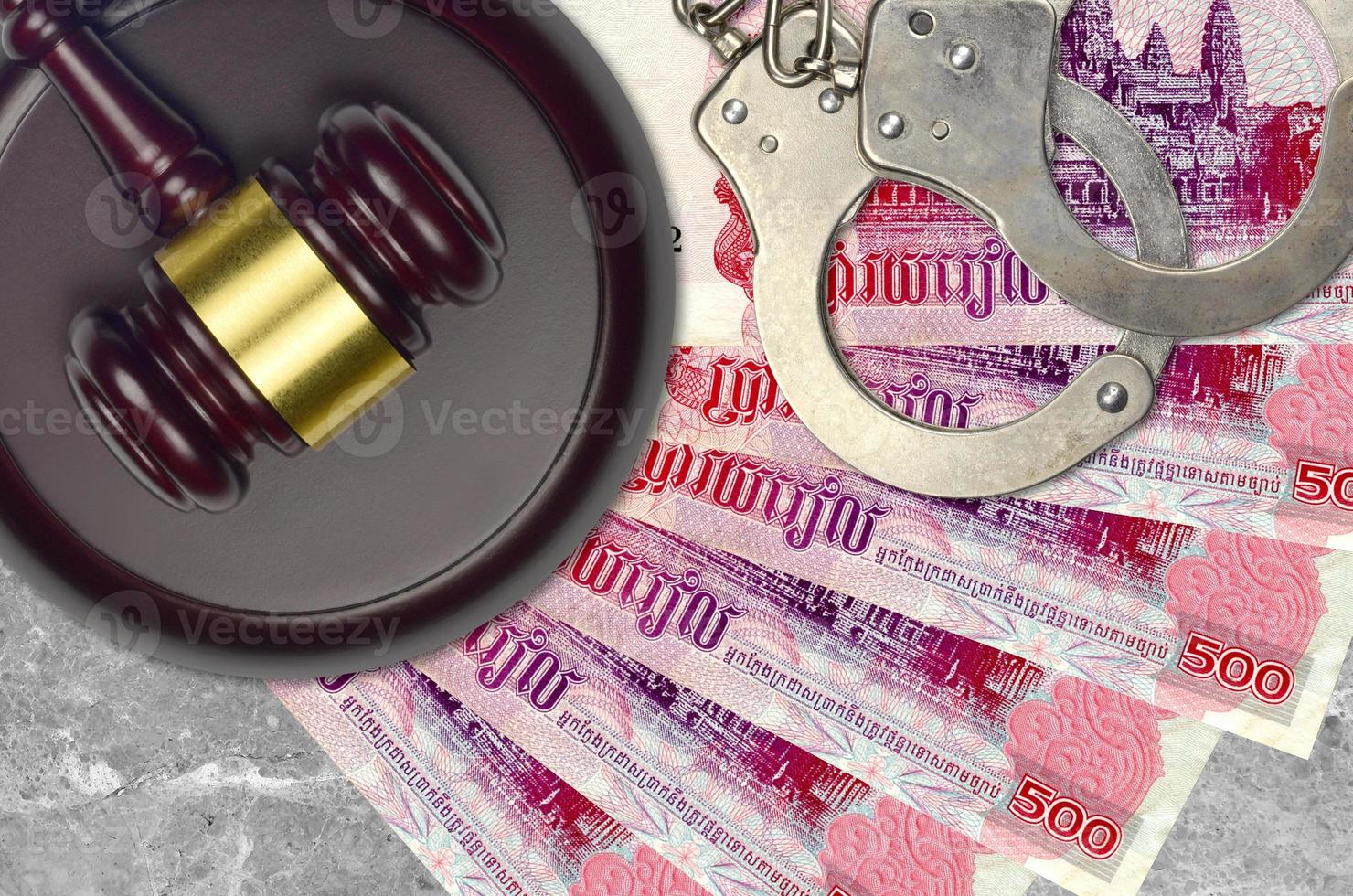 500 Cambodian riels bills and judge hammer with police handcuffs on court desk. Concept of judicial trial or bribery. Tax avoidance photo