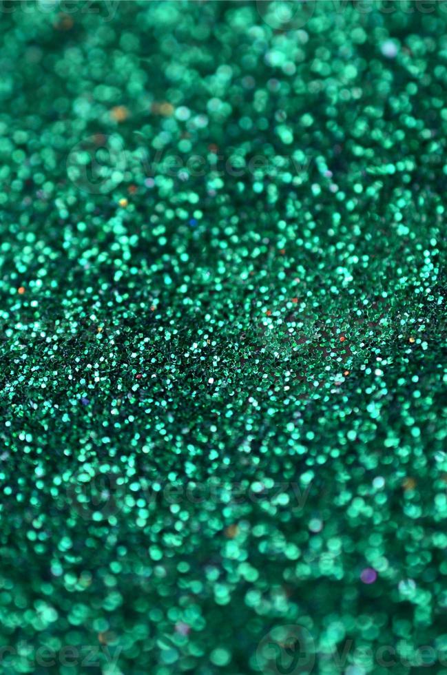 una gran cantidad de lentejuelas decorativas verdes. textura de fondo con elementos pequeños y brillantes que reflejan la luz en un orden aleatorio. textura brillo foto