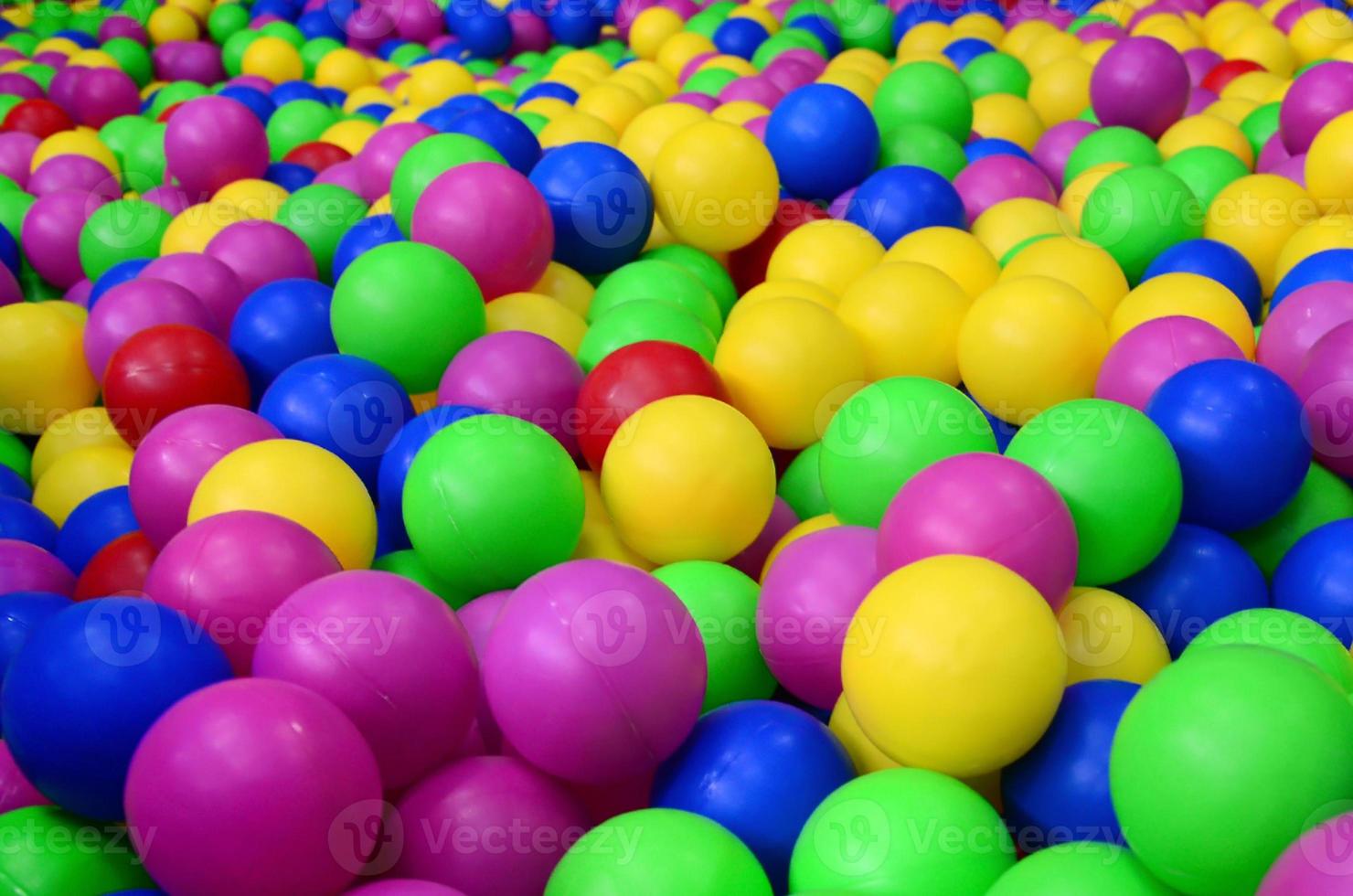 Many colorful plastic balls in a kids' ballpit at a playground. Close up pattern photo