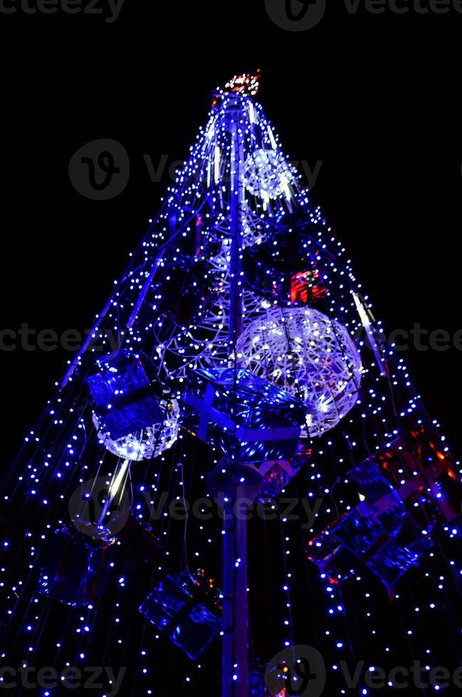 Fragment of the New Year tree. A lot of round lights of blue color are located on a conical frame photo