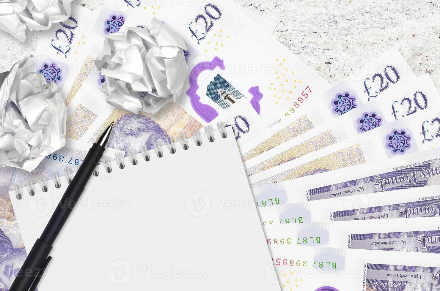 20 British pounds bills and balls of crumpled paper with blank notepad. Bad ideas or less of inspiration concept. Searching ideas for investment photo