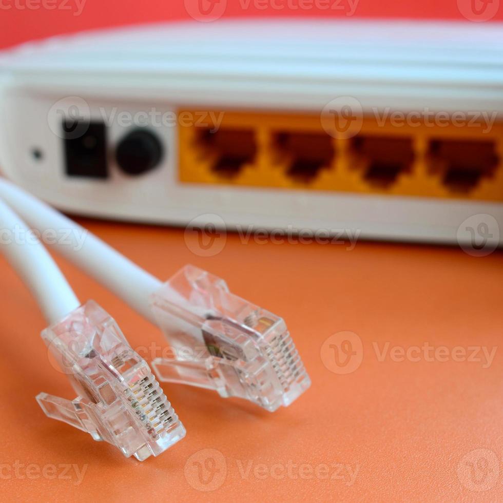 el enrutador de Internet y los enchufes del cable de Internet se encuentran sobre un fondo naranja brillante. elementos necesarios para la conexión a internet foto