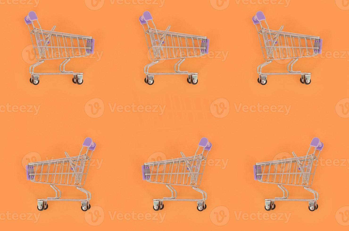 Shopping addiction, shopping lover or shopaholic concept. Many small empty shopping carts perform a pattern on a pastel colored paper background. Flat lay composition, top view photo
