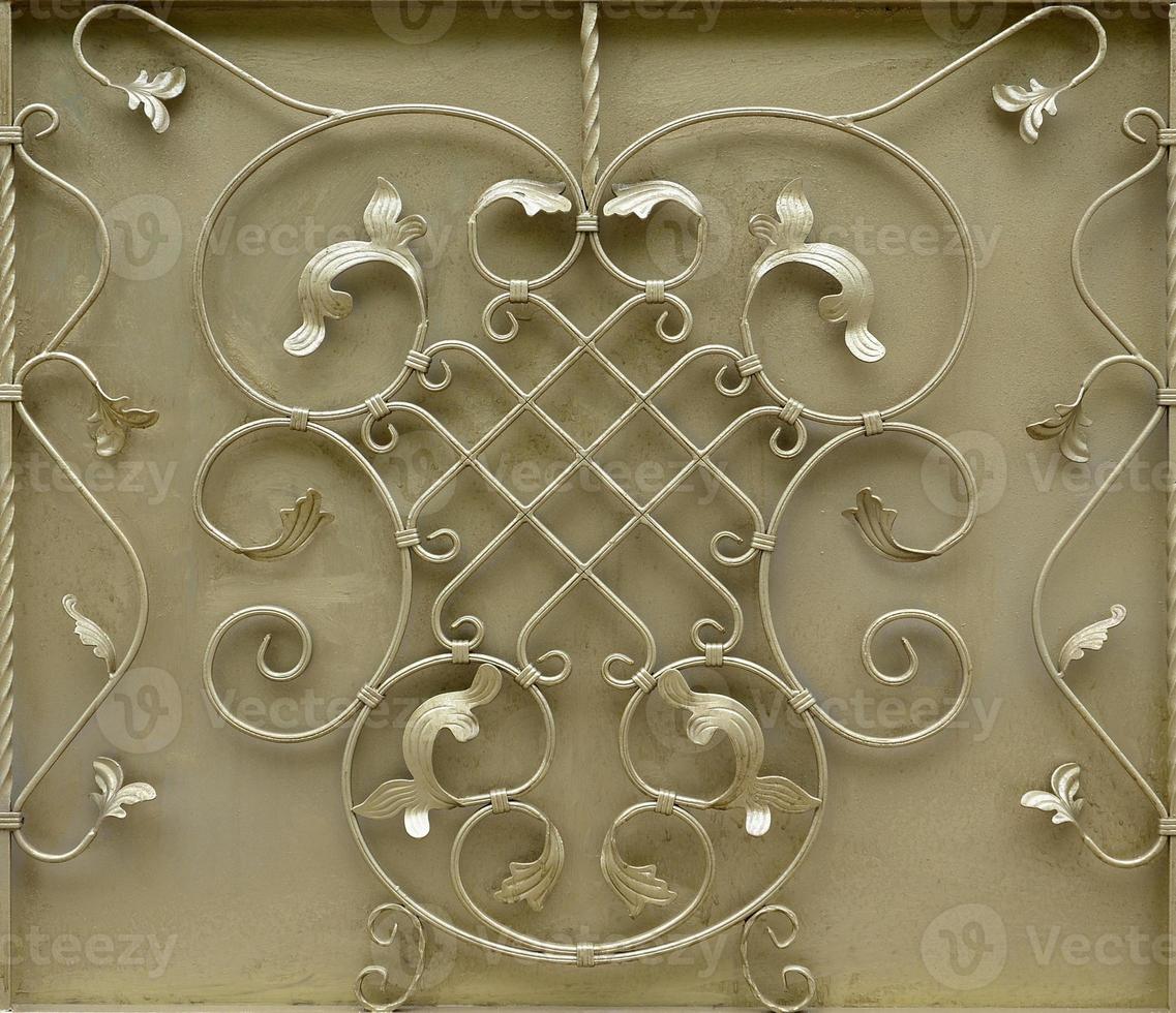 The texture of the golden metal gate with a beautiful floral pattern of forged metal photo