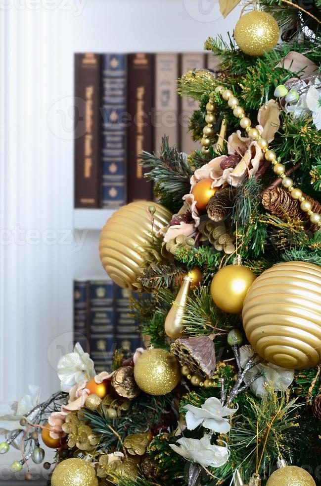 A beautiful decorated Christmas tree on the background of a bookshelf with many books of different colors. Christmas background image of the library photo