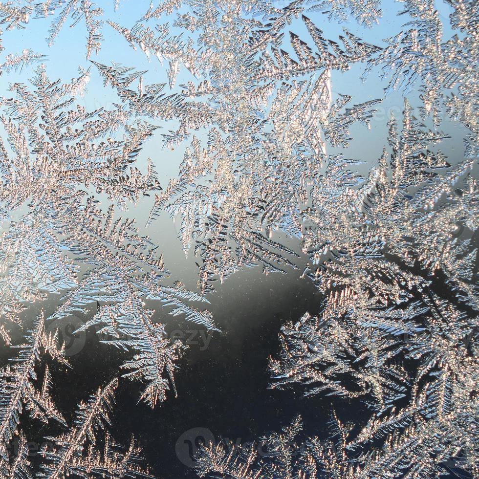 Snowflakes frost rime macro on window glass pane photo