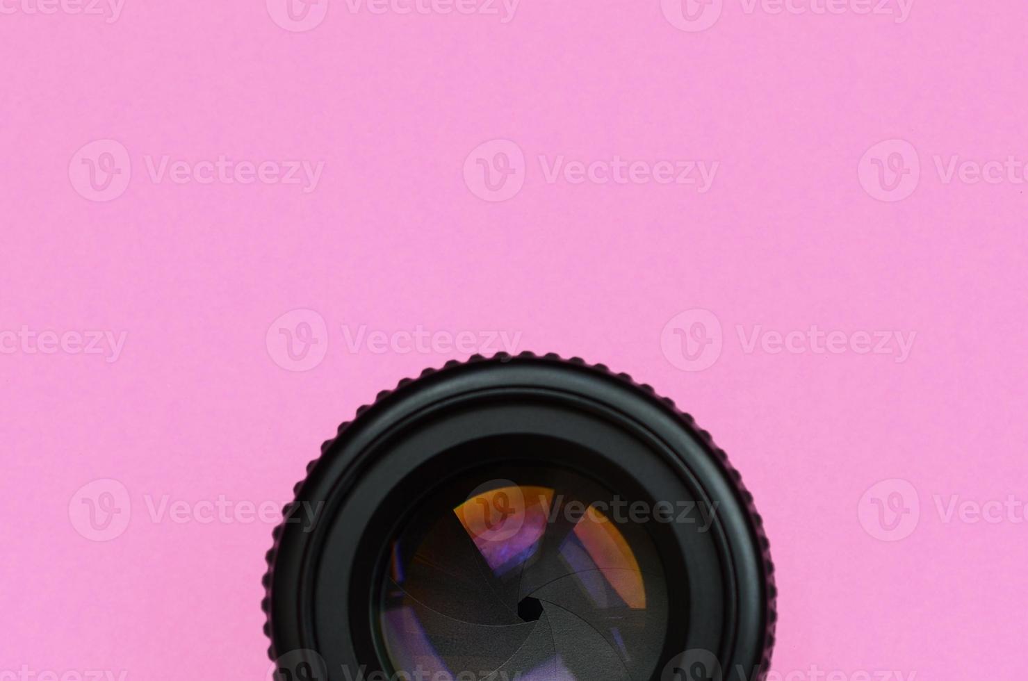 Camera lens with a closed aperture lie on texture background of fashion pastel pink color paper in minimal concept photo