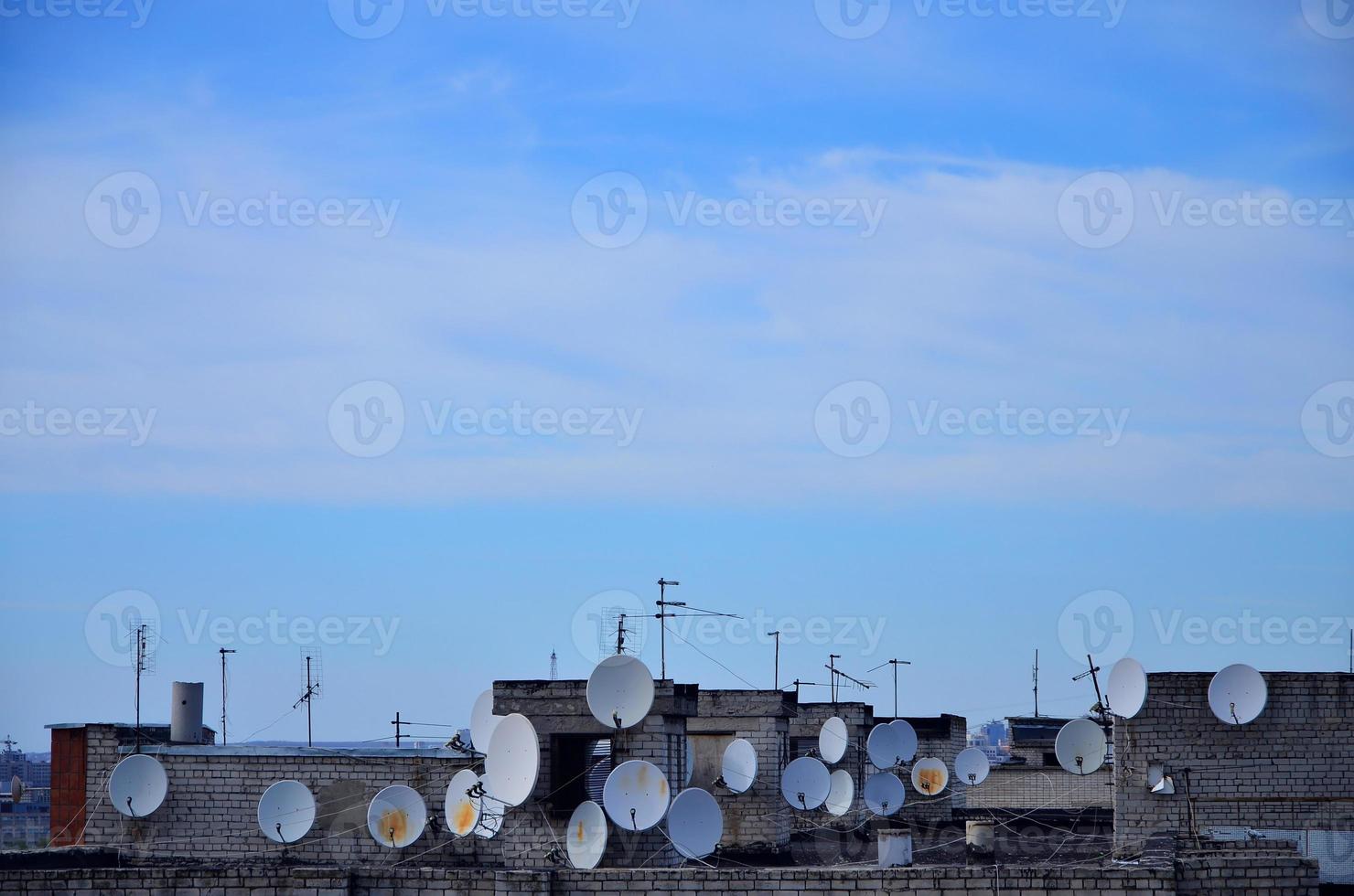 muchas antenas de televisión por satélite en la azotea bajo un cielo azul foto