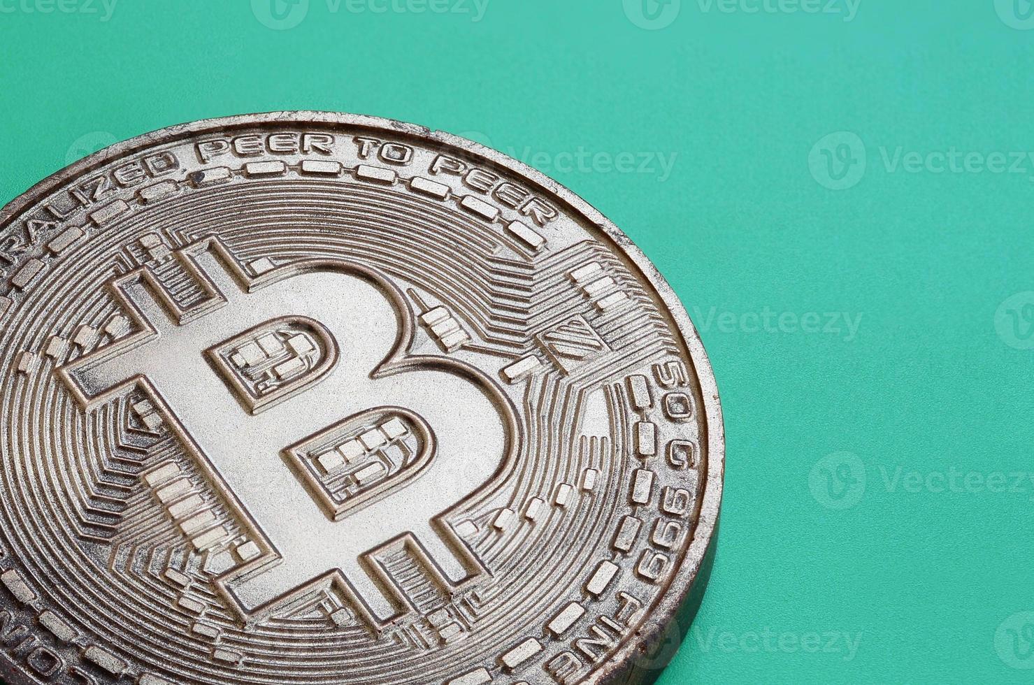 Chocolate product in the form of physical bitcoin lies on a green plastic background. Model of the crypto currency in the edible form photo