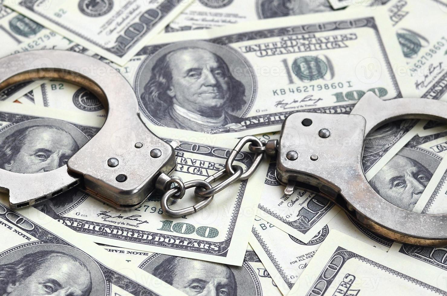 Police handcuffs lie on a lot of dollar bills. The concept of illegal possession of money, illegal transactions with US dollars. Economic Crime photo