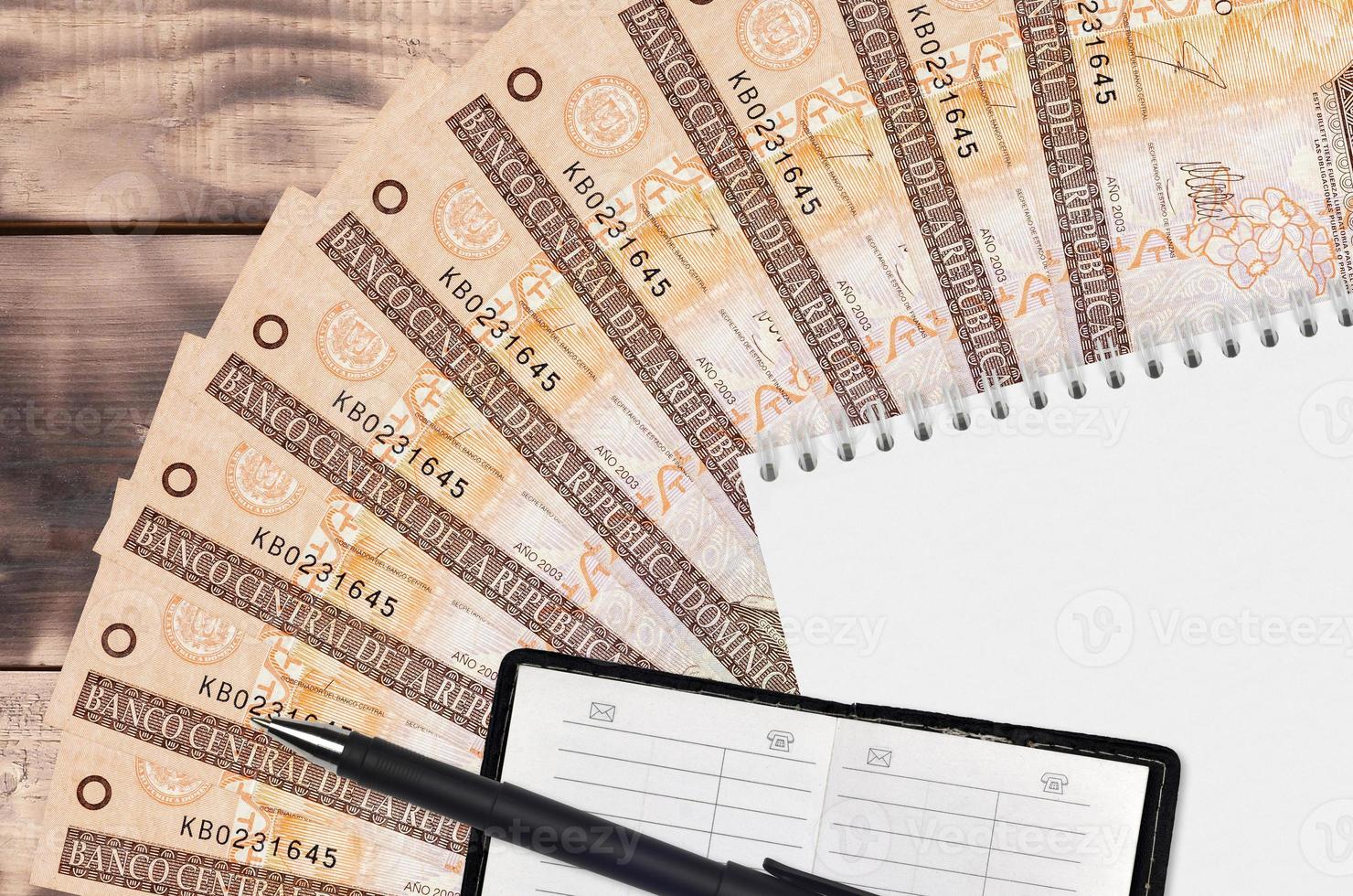 20 Dominican peso bills fan and notepad with contact book and black pen. Concept of financial planning and business strategy photo