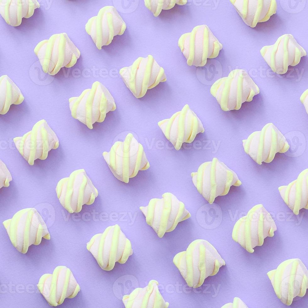 Colorful marshmallow laid out on violet paper background. pastel creative textured pattern. minimal photo