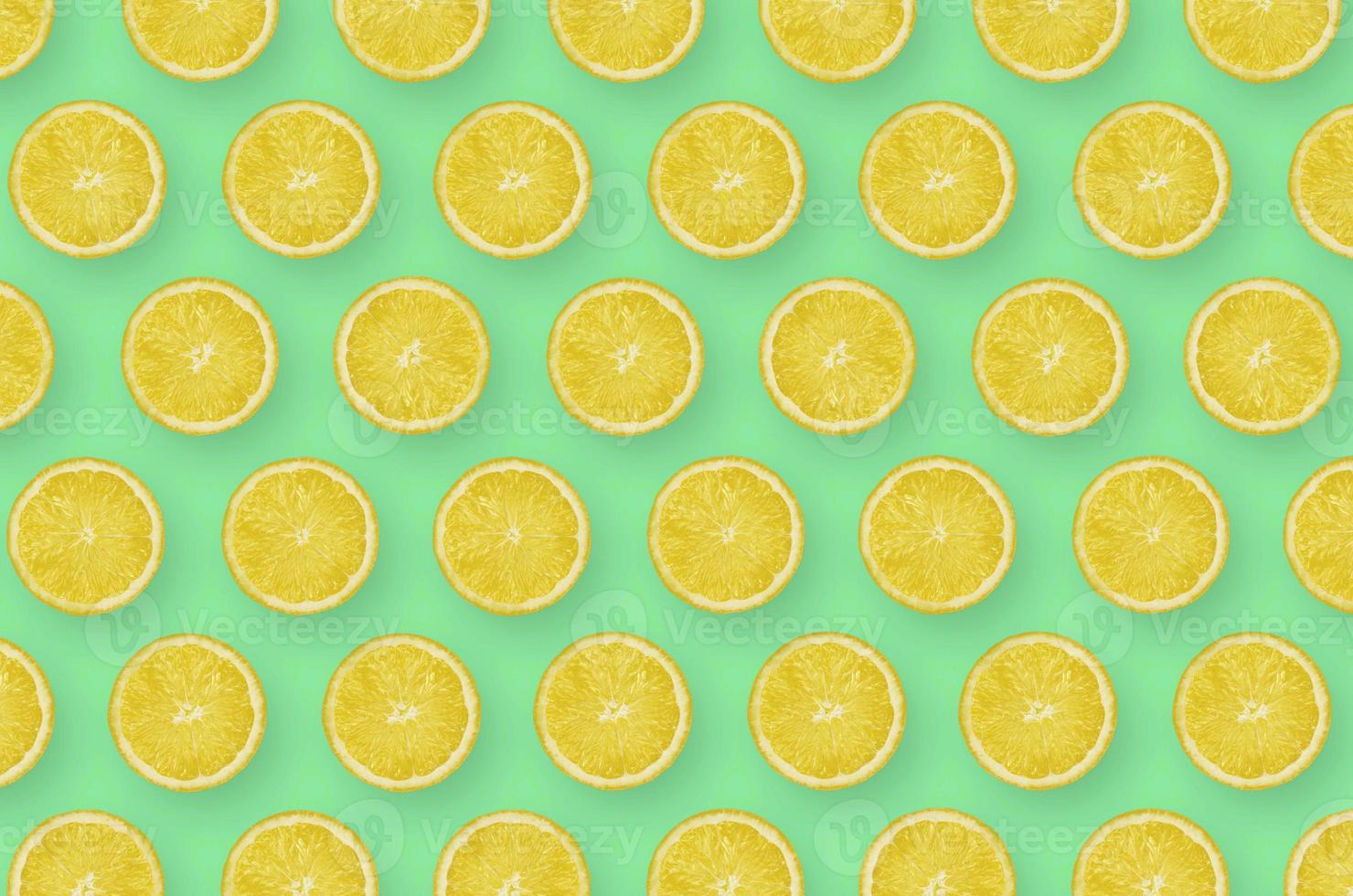 Pattern of yellow lemon citrus slices on bright green background photo