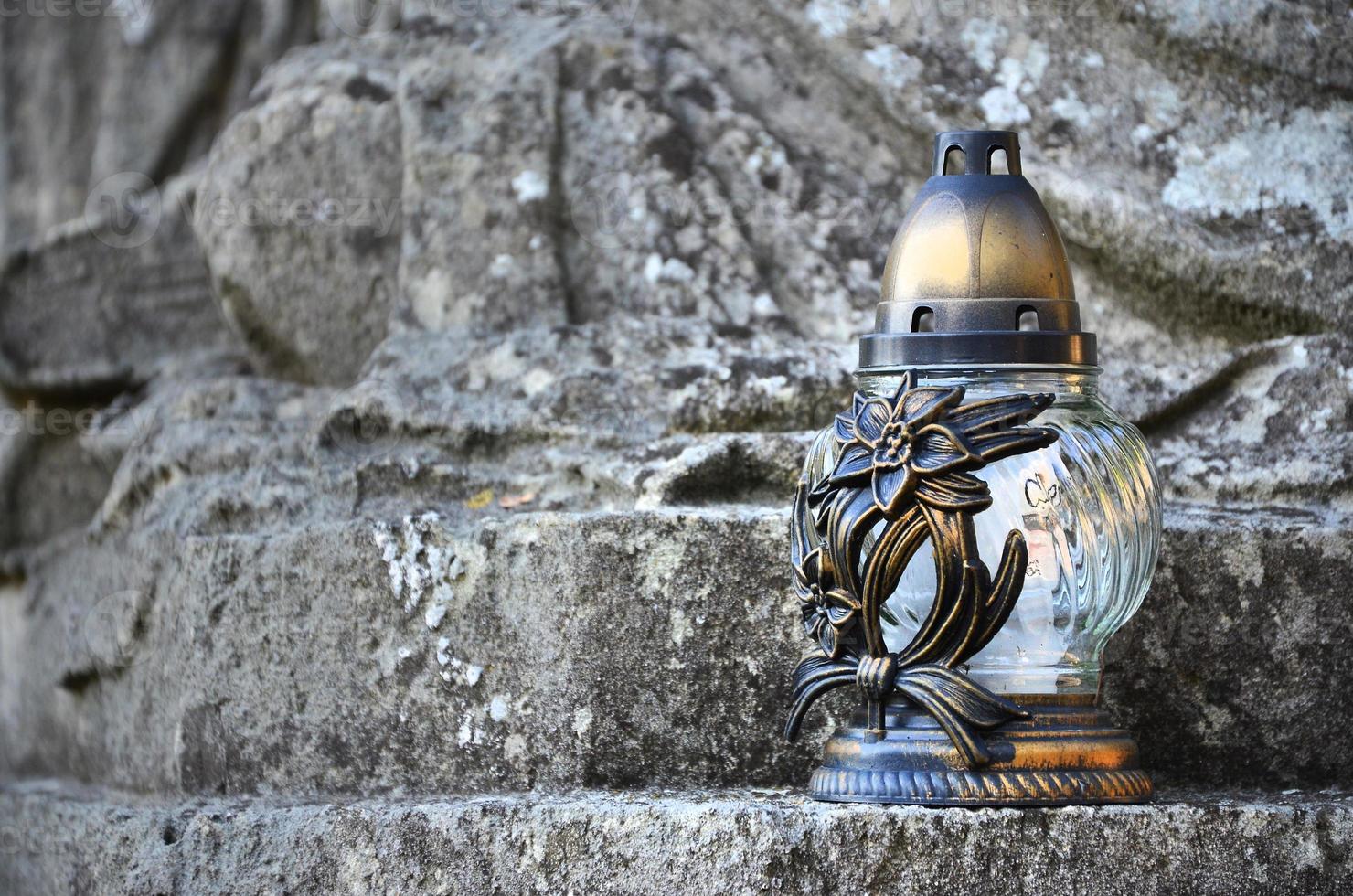 A metal lamp stands on the stone surface of an old crypt photo