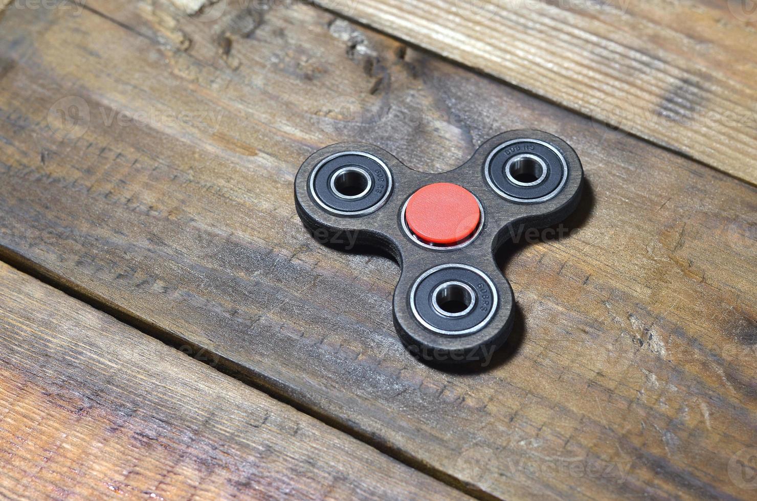 A rare handmade wooden fidget spinner lies on a brown wooden background surface. Trendy stress relieving toy photo