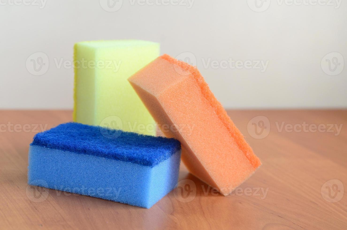 A few kitchen sponges lie on a wooden kitchen countertop. Colorful objects for washing dishes and cleaning in the house are ready for use photo