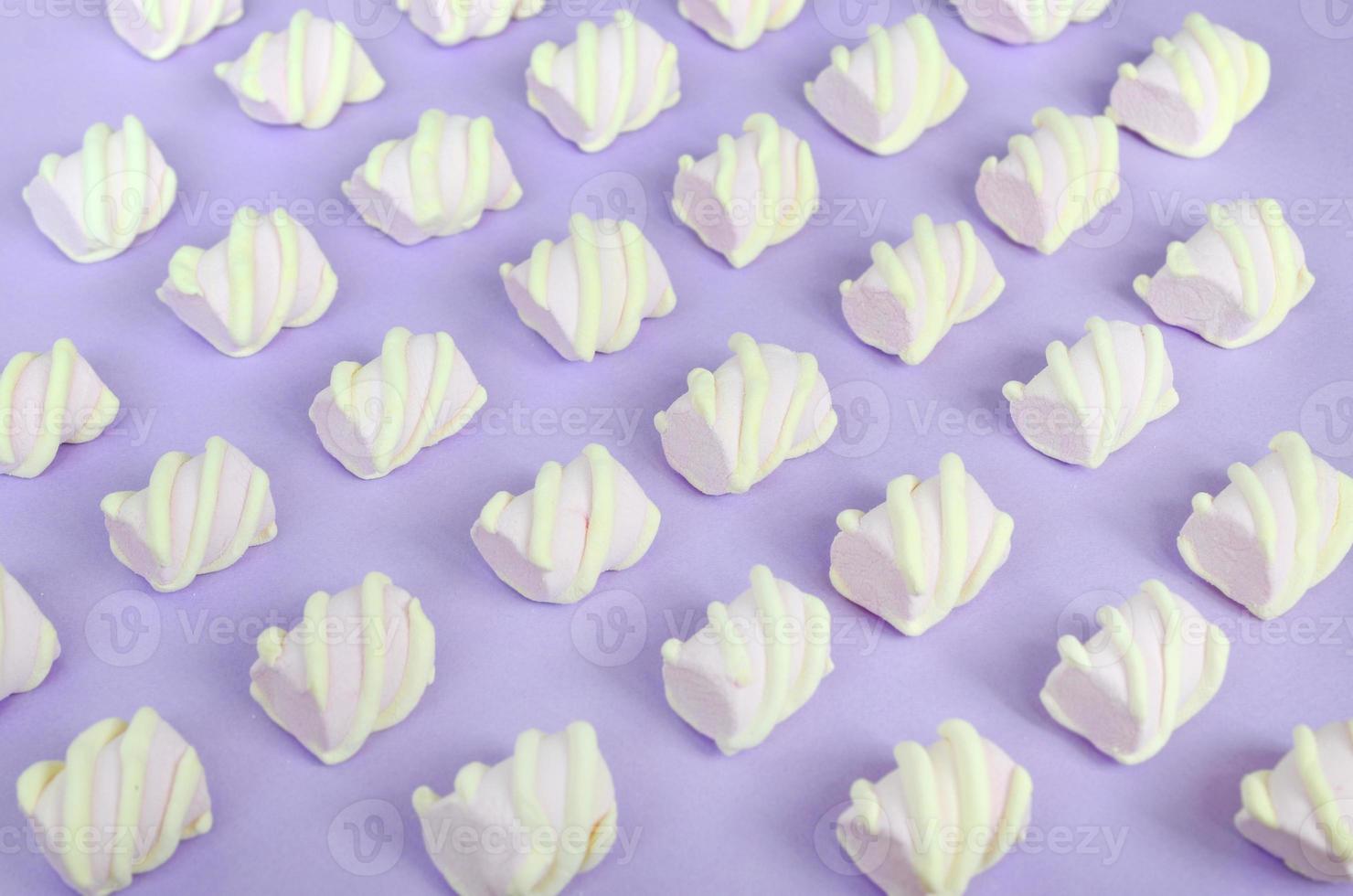 Colorful marshmallow laid out on violet paper background. pastel creative textured pattern. Perspective macro shot photo