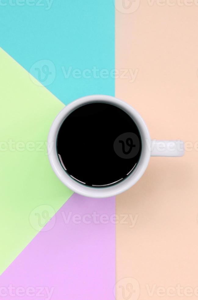 Small white coffee cup on texture background of fashion pastel pink, blue, coral and lime colors paper photo