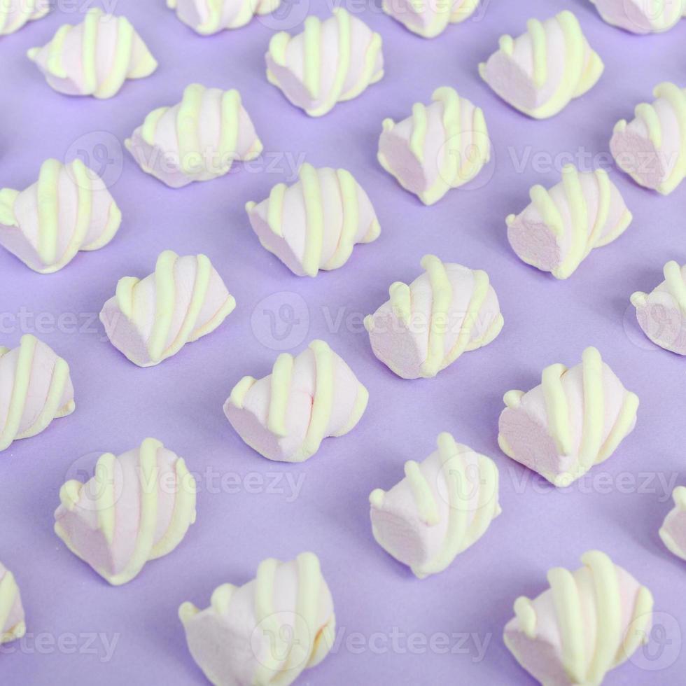 Colorful marshmallow laid out on violet paper background. pastel creative textured pattern. Perspective macro shot photo