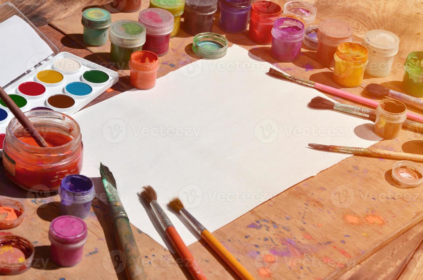 Still life with blank paper, brushes and jars of watercolor and gouache paint photo